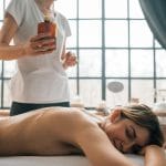 Kobieta na relaksującym masażu w spa trzymająca buteleczkę olejku